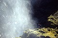 Spray from a waterfall over the Markarflj&oacute;t Gorge [Markarfljot Gorge], Iceland. Two figures stand just out of reach.